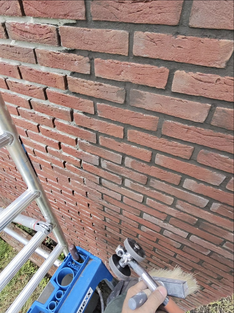 Vakman voegt en werkt metselwerk af op een steiger